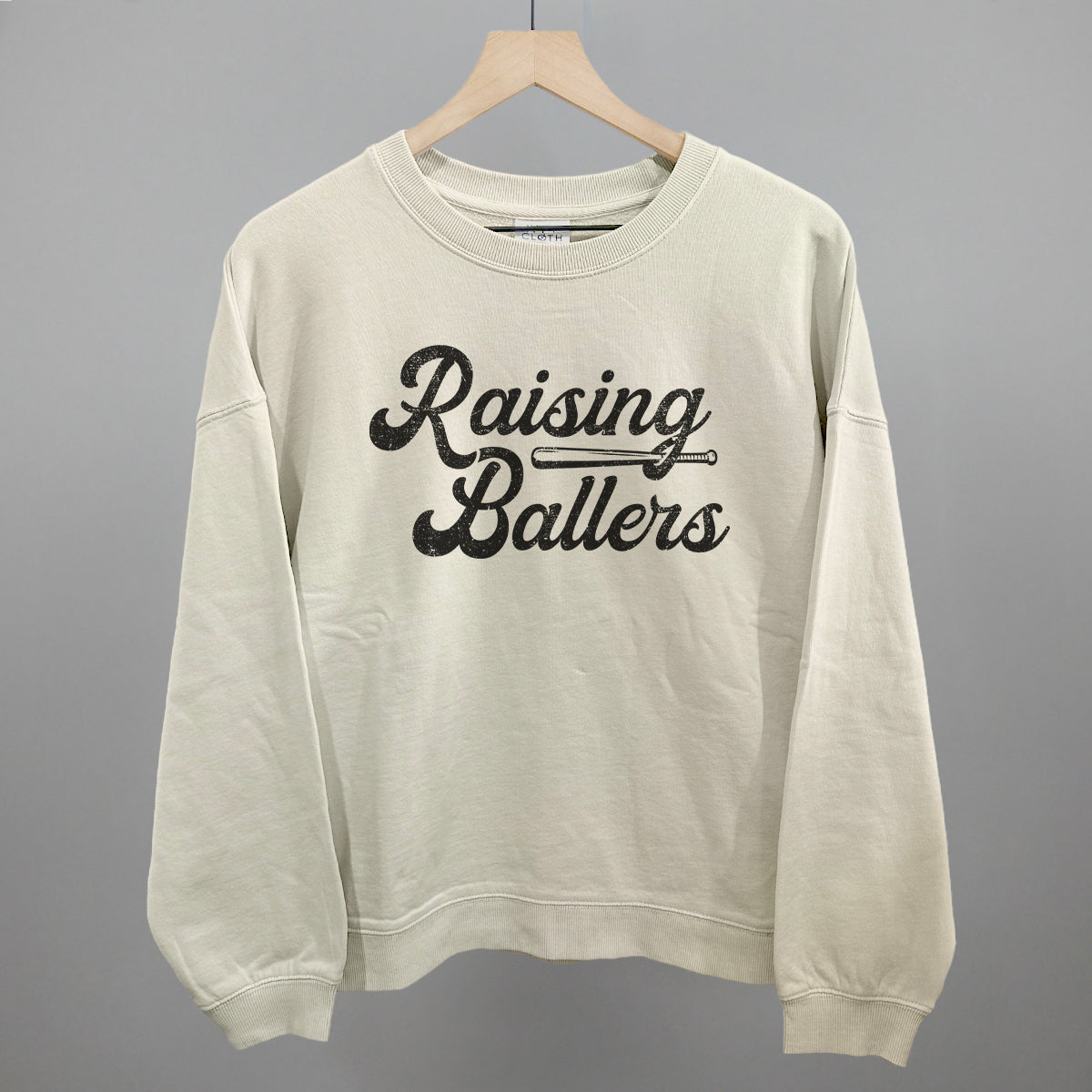 Beige sweatshirt with 'Raising Ballers' text on a gray background