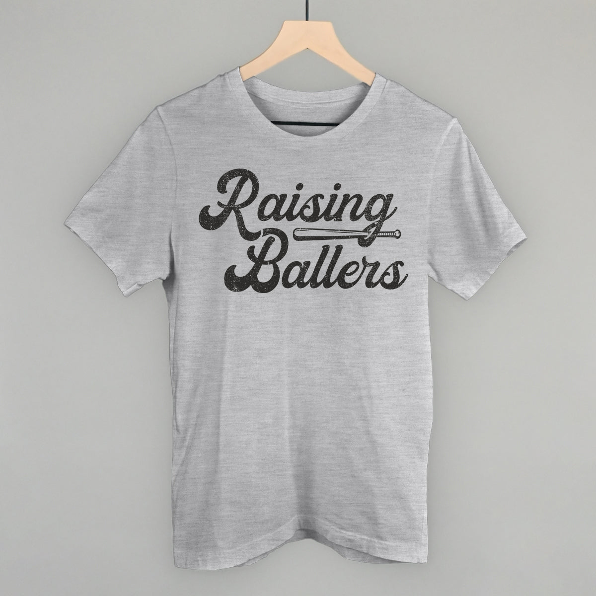 Gray t-shirt with 'Raising Ballers' text on a hanger against a gray background