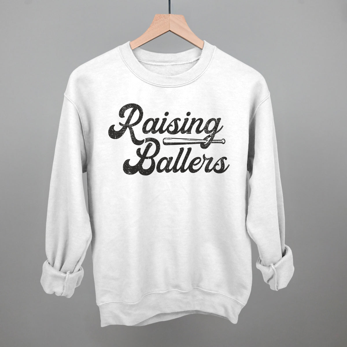 White sweatshirt with 'Raising Ballers' text on a gray background