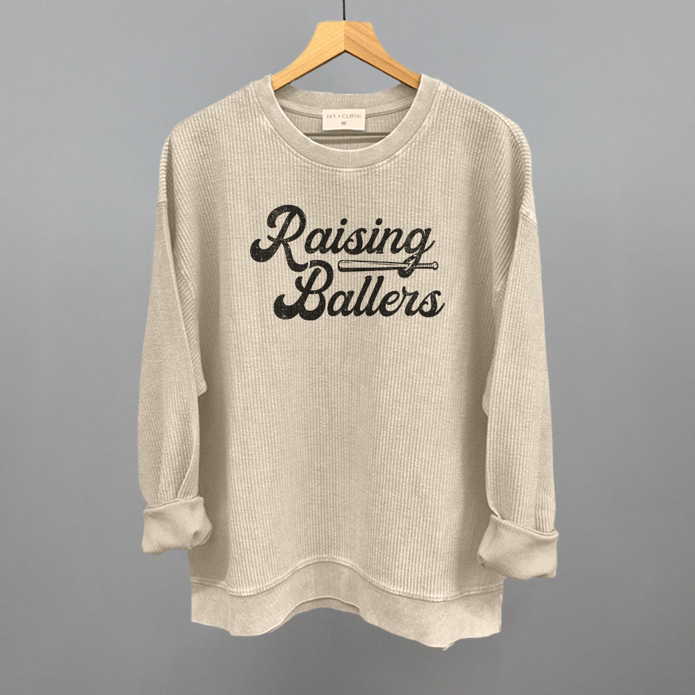 Beige sweatshirt with 'Raising Ballers' text on a hanger against a gray background