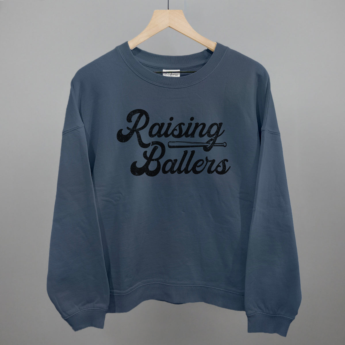 Blue sweatshirt with 'Raising Ballers' text on a gray background