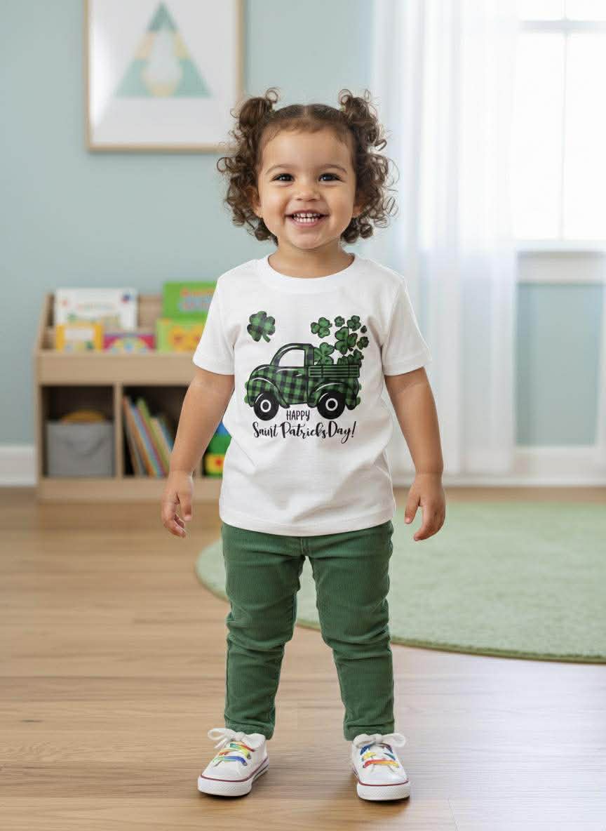Child wearing a St. Patrick's Day-themed t-shirt in a room with a bookshelf.