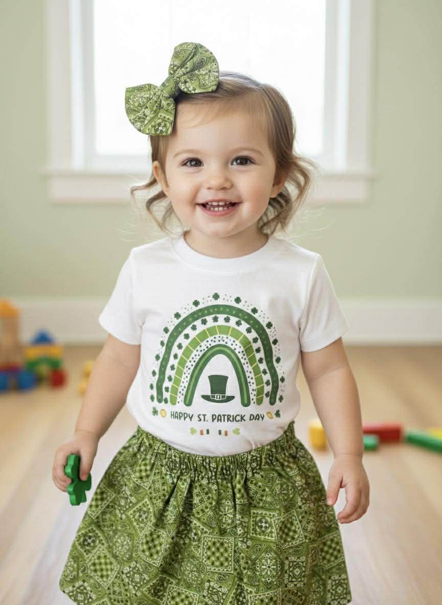 Child wearing a St. Patrick's Day-themed shirt and green headband indoors.
